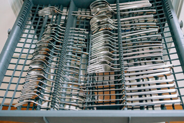 open dishwasher with a pull-out compartment for clean spoons and forks . High quality photo