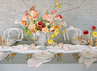 Elegant tabletop arrangement with flowers, glassware, and tableware at a modern setting during daylight