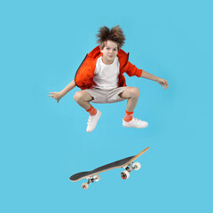 Cute little boy with skateboard in air on light blue background. Performing trick