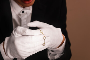 Appraiser with luxury jewelry on brown background, closeup