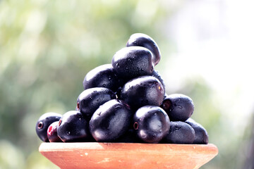 Raw Black Jamun with its tree shown in the background in Blur.point focus.