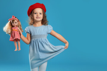 Obraz premium Cute little girl with doll on light blue background. Space for text