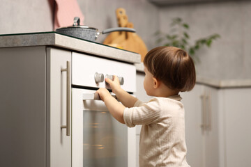 Little boy playing with oven in kitchen. Dangerous situation