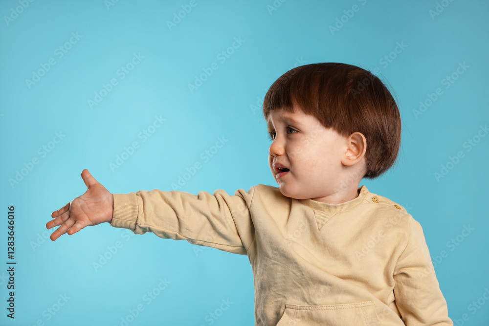 Wall mural Portrait of emotional little boy on light blue background