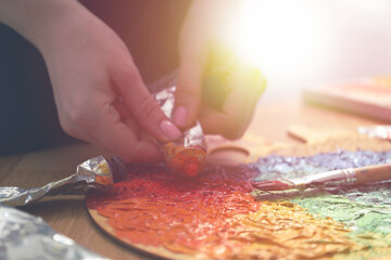 Artist squeezing paint onto palette in sunlit studio, closeup