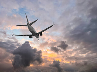 Airplane flying in beautiful sky with clouds at sunset