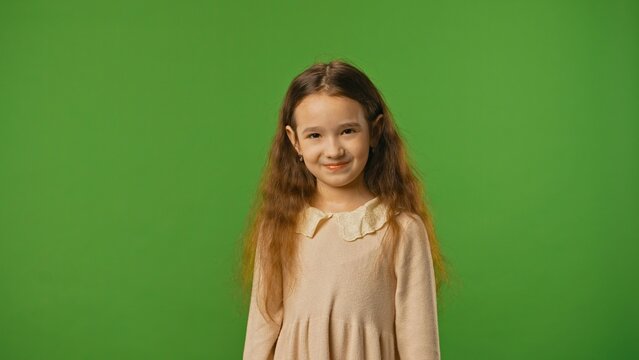 Little girl child in shirt standing looking at camera, isolated on chroma key green screen studio background mockup.
