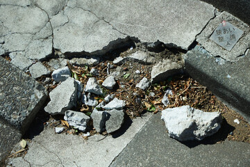 Concrete that has decayed over time. Shattered to pieces, the soil underneath is visible.