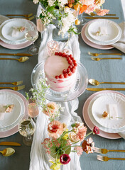 Elegant dessert table set for a celebration featuring a beautiful cake and floral arrangements during a sunny afternoon gathering