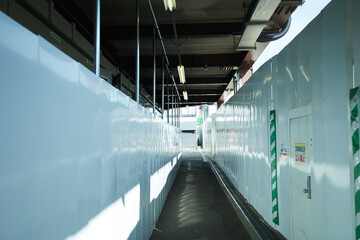 A narrow path between large white walls. Near a station under renovation in Tokyo, Japan. White impulse.