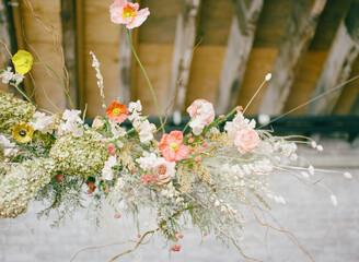 Beautiful floral arrangement hanging from the ceiling at a rustic venue adorned with soft colors during a bright afternoon