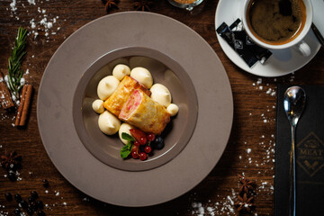 Crispy pastry with berry filling, served with vanilla cream dollops. Decorated with red currants, blueberries, and mint. Sophisticated dessert closeup in modern gourmet restaurant