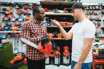 A sales consultant helps a client choose an electric saw in a hardware store
