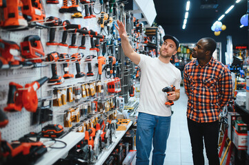 A sales consultant helps a client choose a screwdriver in a hardware store