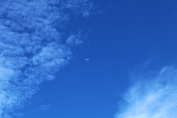The morning blue sky is decorated with white clouds and the moon is still visible.