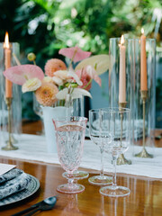 Elegant table setting with candles and floral arrangements in a lush outdoor setting during a gathering