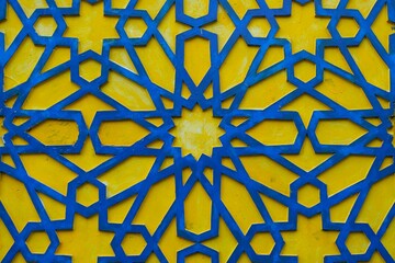 Intricate Islamic geometric pattern in blue and yellow on the mosque wall