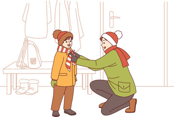 Caring father helps kid put on winter clothes so as not to freeze while walking along cold street. Happy father tying scarf to child showing care and desire to help smiling pre-teen son