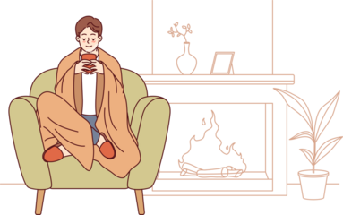 Man feels comfort and harmony sitting by fireplace with blanket on shoulders and cup of hot coffee in hands. Guy enjoys comforts of home and apartment is cozy, allowing him to relax on winter evenings