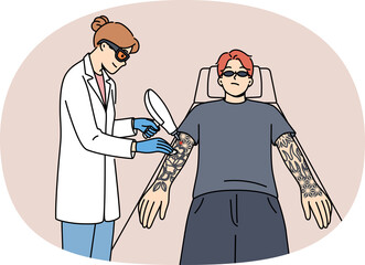 Procedure for laser tattoo removal from guy arms, with professional woman doctor. Casual man wants to get rid of tattoos made at young age and interfering with professional growth.