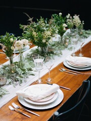 Elegant dining setup with floral arrangements on a long table during a celebration in a modern venue