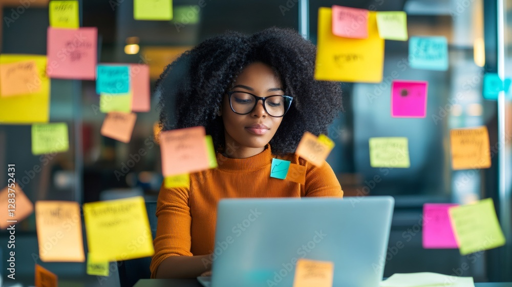 Poster Young project manager using laptop and organizing work with colorful sticky notes on glass wall in modern office, focusing on efficient task management and deadline prioritization