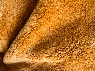 Soft golden fabric close-up reveals intricate textures and patterns in bright light