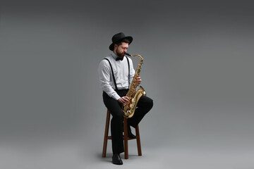 Naklejka premium Professional musician playing saxophone on grey background