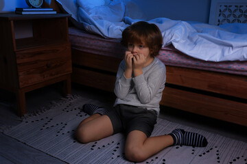 Afraid boy near his bed at night