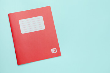 One copybook on light blue background, top view. School stationery