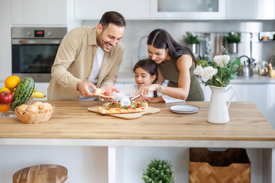 Family enjoys cooking together in a bright kitchen while preparing fresh pizza for dinner