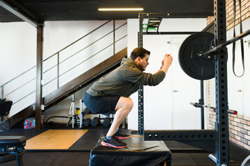 Middle aged chubby man performing box squats in a gym, focusing on strength and fitness training