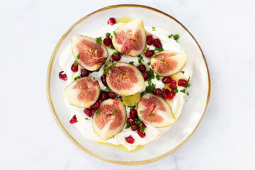 Delicious fig healthy garnished with pomegranate on greek yogurt and virgin olive oil.
