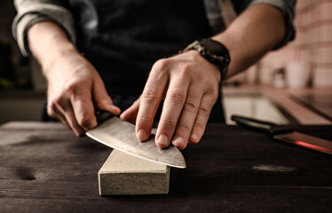 Man sharpening a knife with whetstone