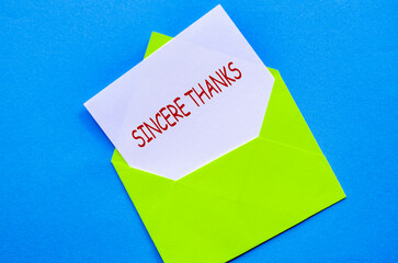 Green envelope on a blue cover with a white card partially pulled out with Sincere Thanks text