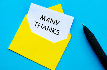 Yellow envelope on a blue cover with a white card partially pulled out with Many Thanks text