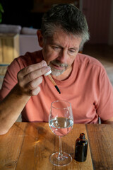 Microdose, Man with a dropper pipette taking the micro dose drug. Medicine CBD, LSD and cannabis oil in liquid form. Psychedelic, hallucinogenic. Alternative medicine.