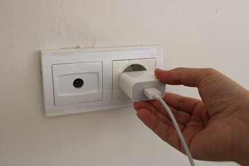 a hand plugging in a phone charger