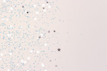 Silver stars and crystals confetti on a glittering background. Shiny concept with place for your design.