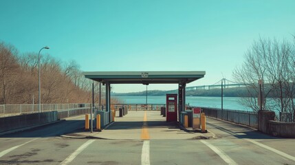 A toll booth on a bridge spanning a wide river. Featuring moderate traffic and a sunny afternoon