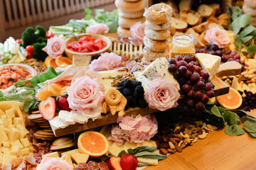 Colorful cheese platter featuring assorted fruits, flowers, and snacks for a lively gathering