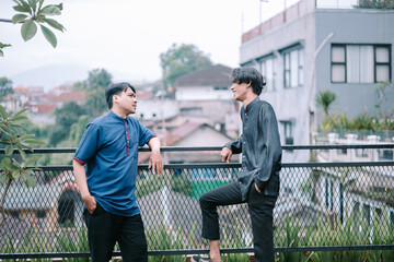 Two young men in casual wear conversing outdoors on an overcast day