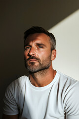 Obraz premium Bearded Man Sitting in Warm Sunlight with Dramatic Shadows