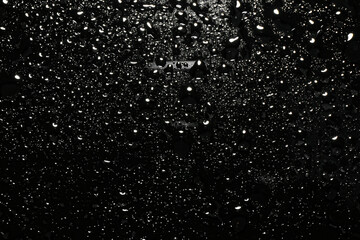 Water drops on black glass surface, top view