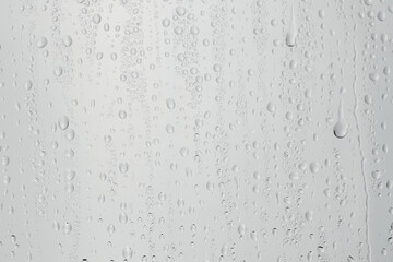 Water drops on light grey glass surface, closeup