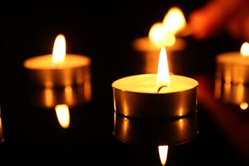 Burning candles on surface in darkness, closeup