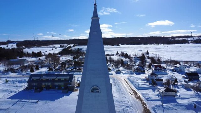 Aerial shot descending from the stone brick facade of the Assomption-de-Notre-Dame Church from the cross of the bell tower, to the large windows all the way to the ground.