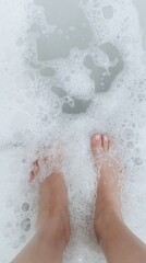 Un par de pies sumergidos en espuma blanca del mar, disfrutando del contacto refrescante con las olas.