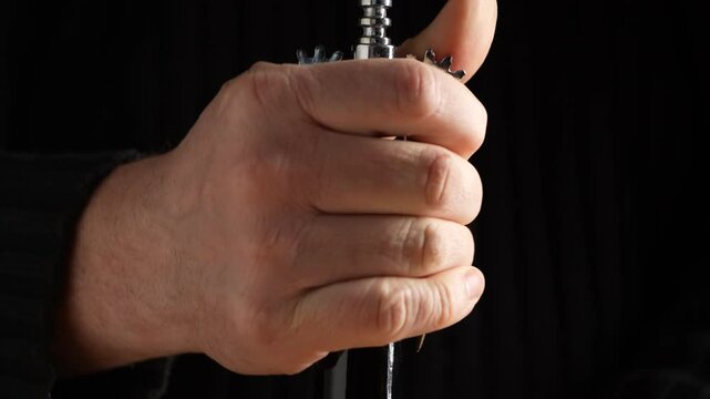 A man opens a bottle of red wine at home. Opening a glass wine bottle with corkscrew, close up
