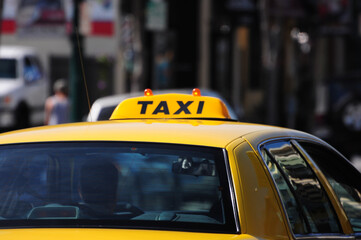 Yellow taxi navigates bustling urban streets, symbolizing city life.